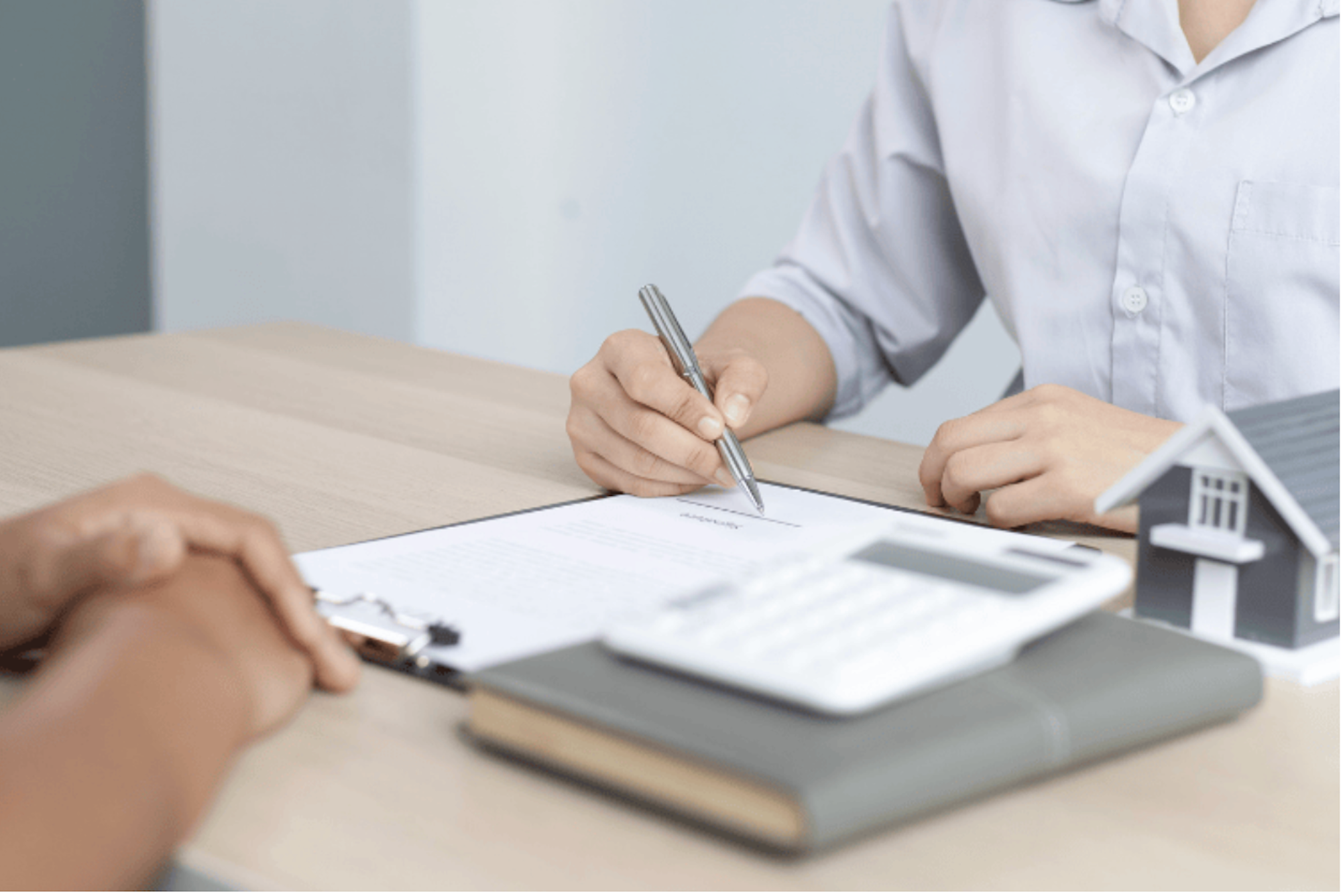 Two people sat across a desk from eachother with a pen and document
