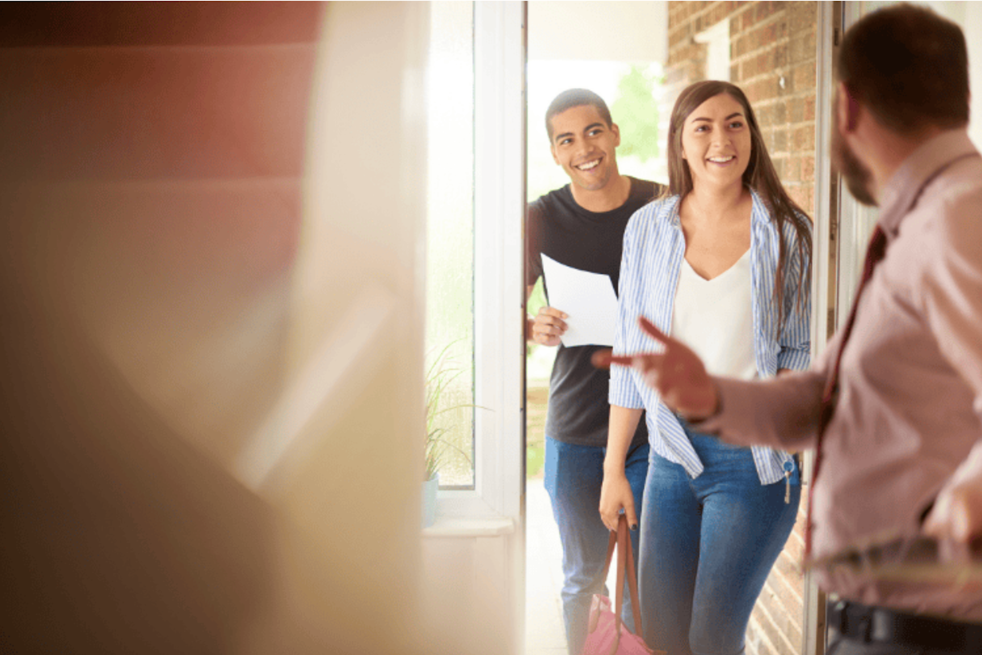 A couple being welcomed into a home by an agent