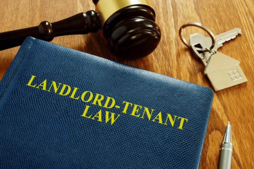 A landlord tenant law book next to keys and a gavel