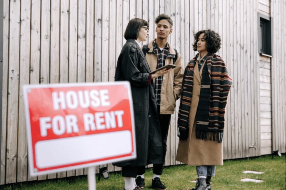 People stood outside a house with a for rent sign