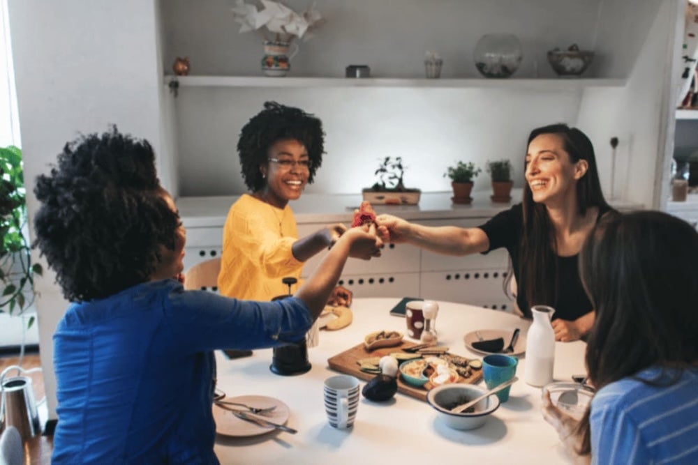 Four roommates sharing food round the table