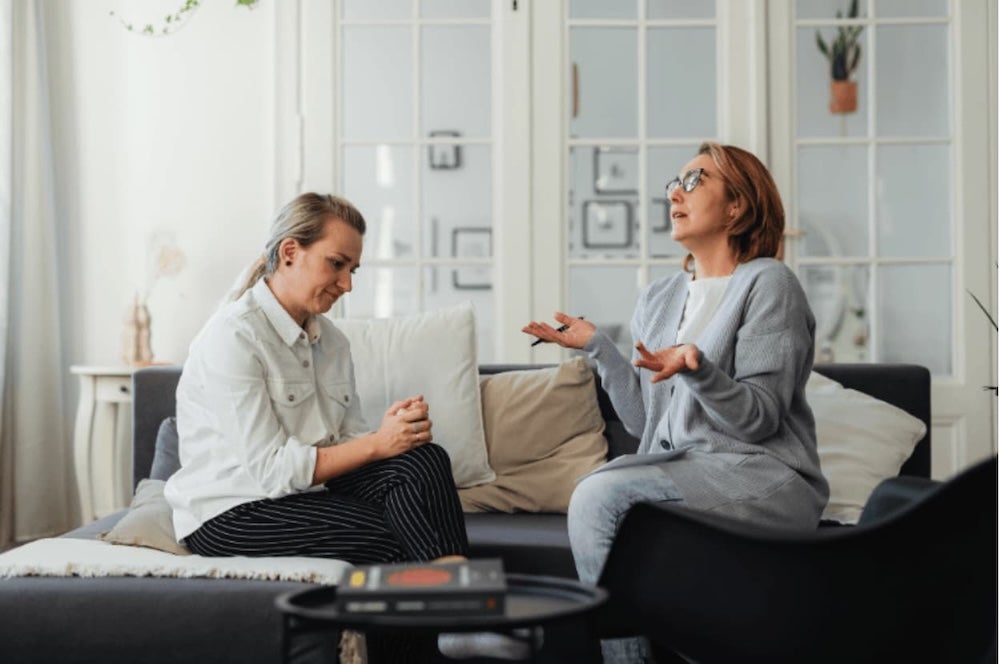 Two women on a couch conversing