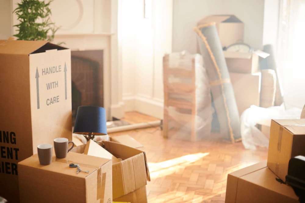 An untidy living room with lots of boxes packing with common household items