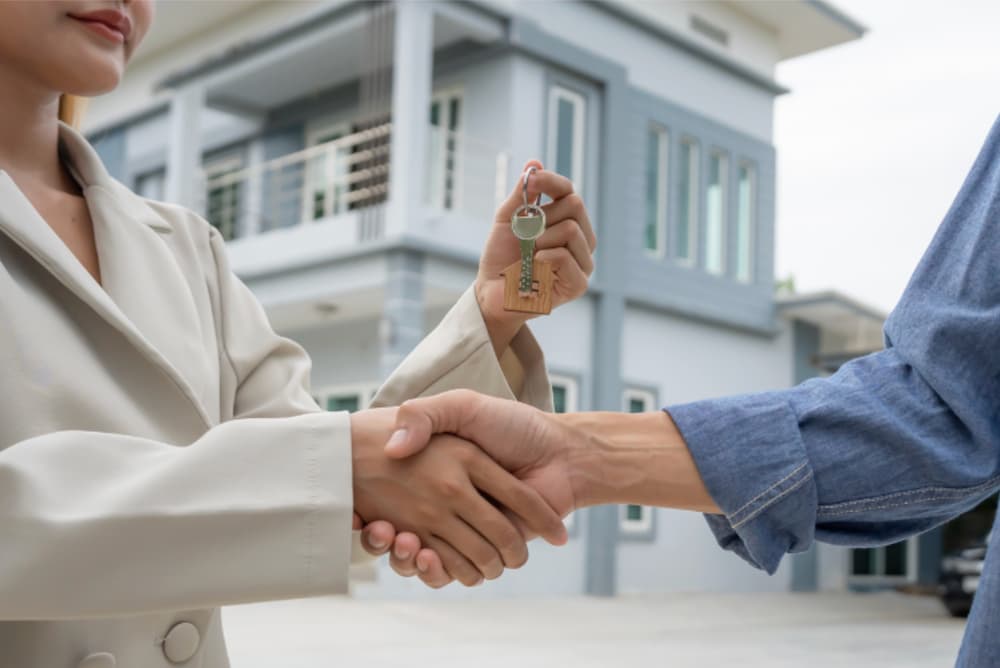 An image of two people shaking hands exchanging a key