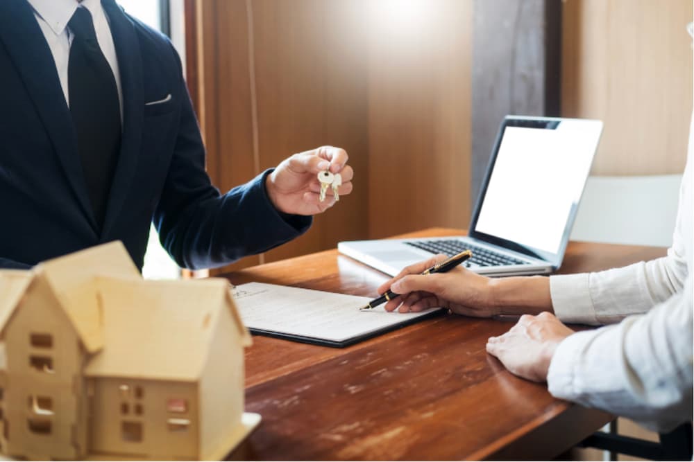 An image of two people sat across a desk with documents exchanging house keys