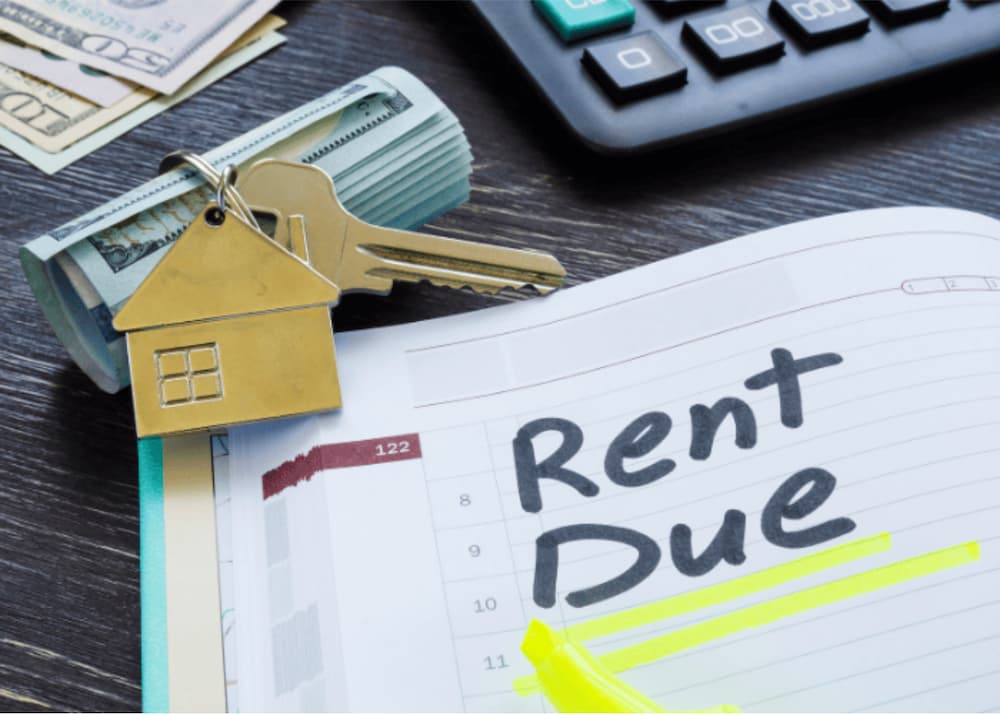 An image of money rolled up next to house keys and a calender with rent due highlighted