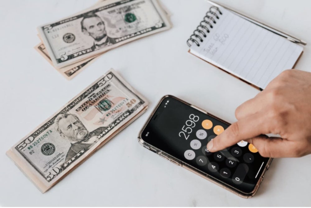 An image of money and a calculator on a desk