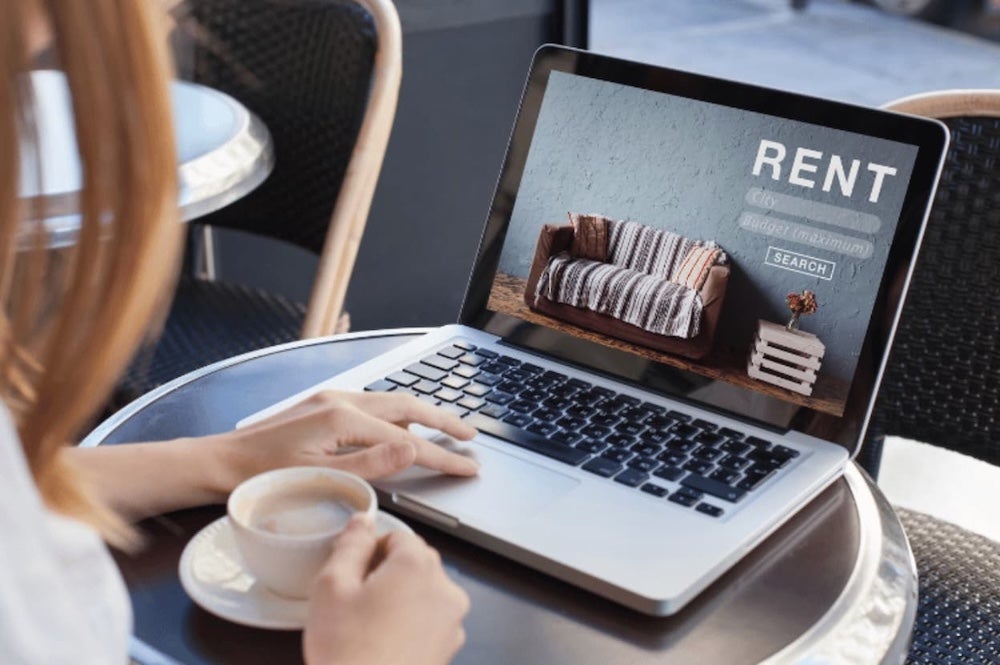An image of someone sat at a desk with a laptop and coffee
