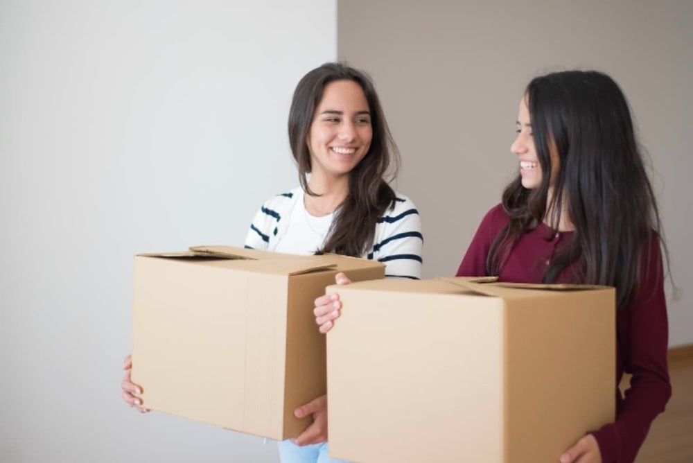 Two roommates carrying moving in boxes