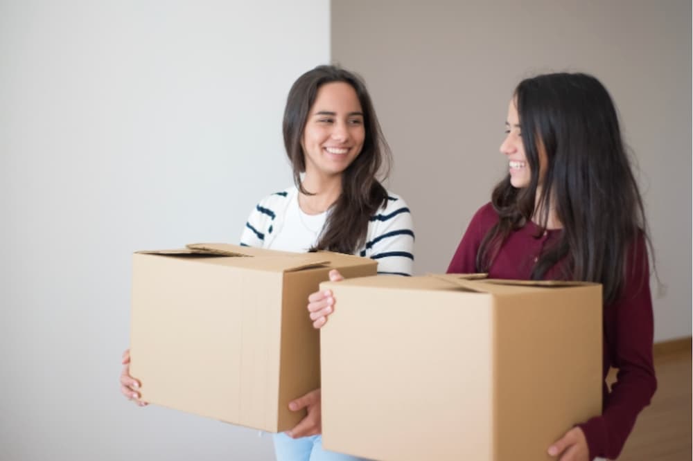 Two roommates carrying moving in boxes