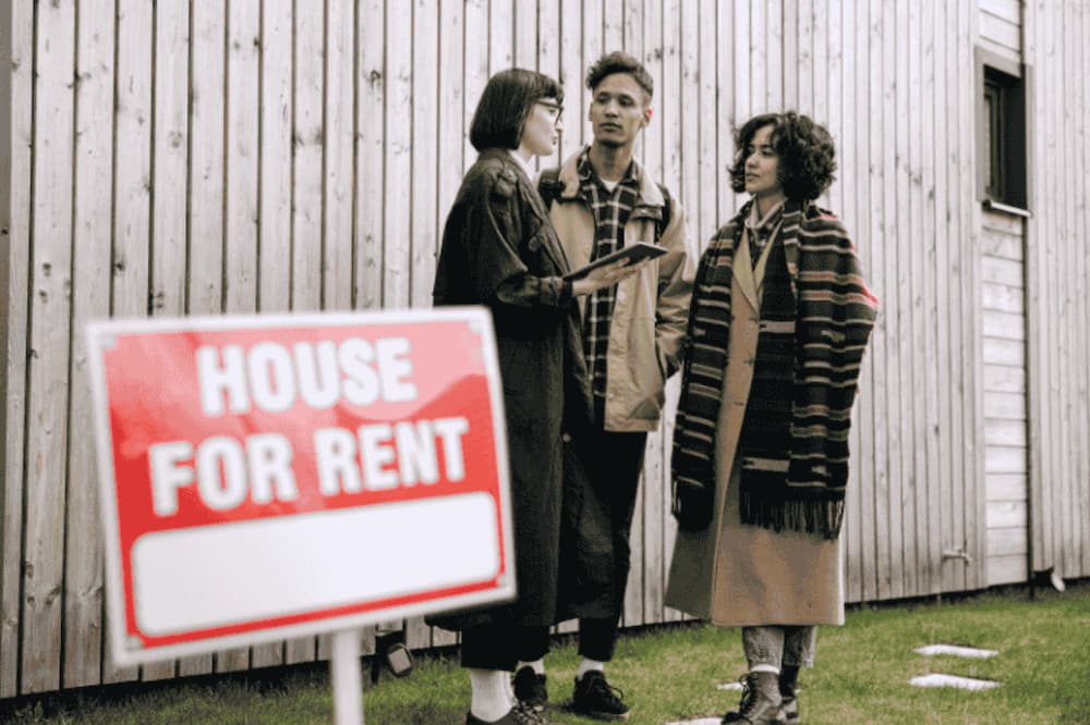 An image of a couple stood outside with an agent by a for rent sign