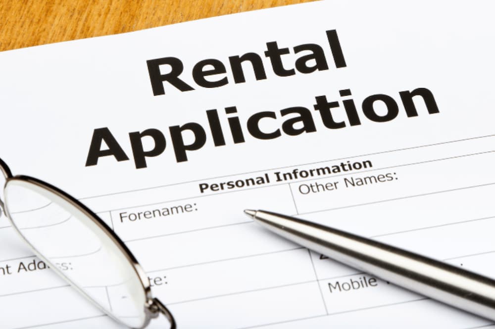 A rental application document on a table with a pen and eye glasses