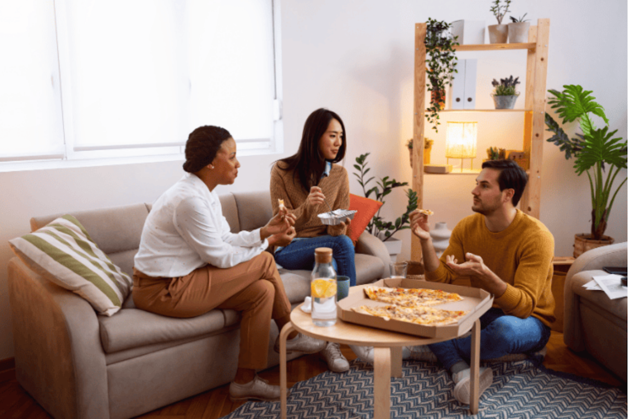 Three people sharing a pizza in a living room