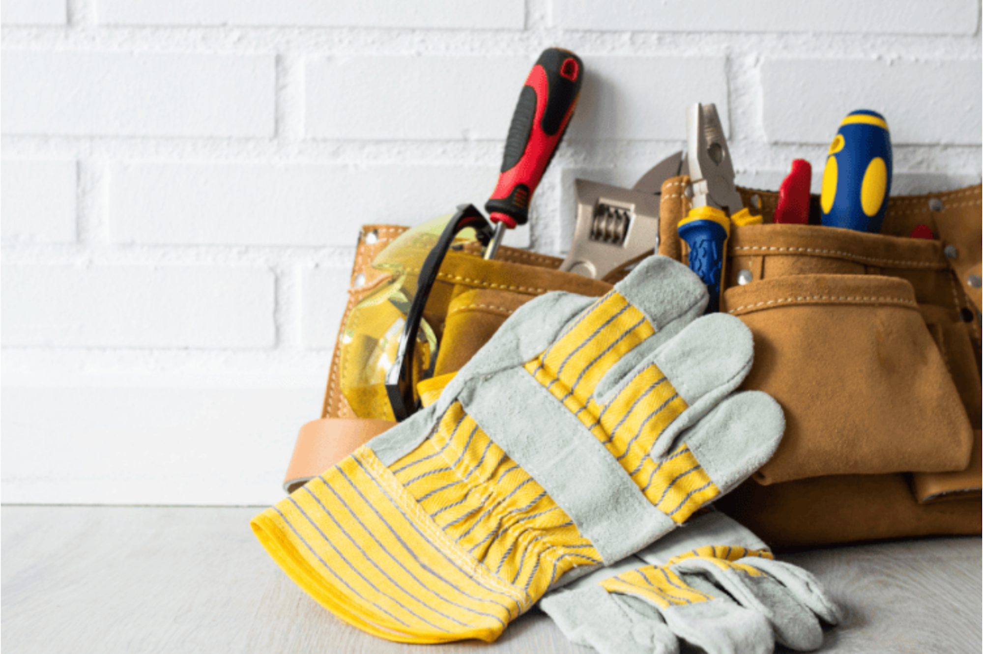 An image of work gloves and a tool belt with tools