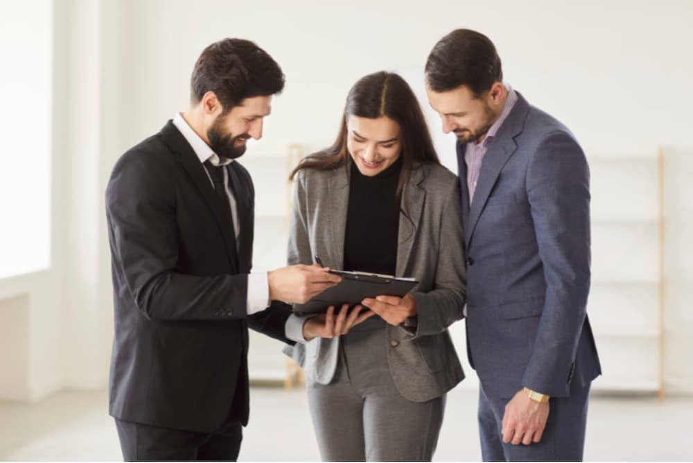 An image of three people huddling around a clip board