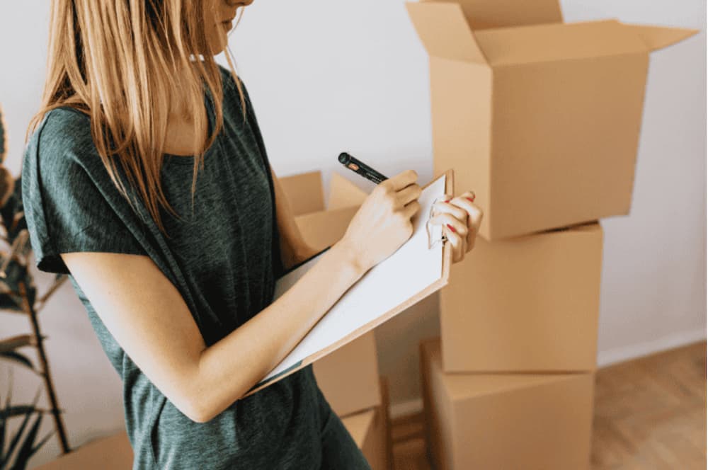 An image of a woman with a checklist and pen looking and packing boxes