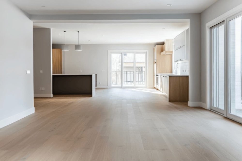 An empty living room leading into an open plan kitchen