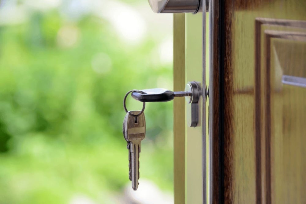 A key in a door with a green nature backdrop