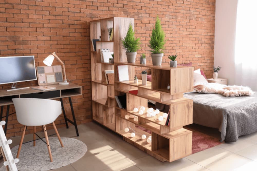 An image of a desk and living room seperated by a shelving unit