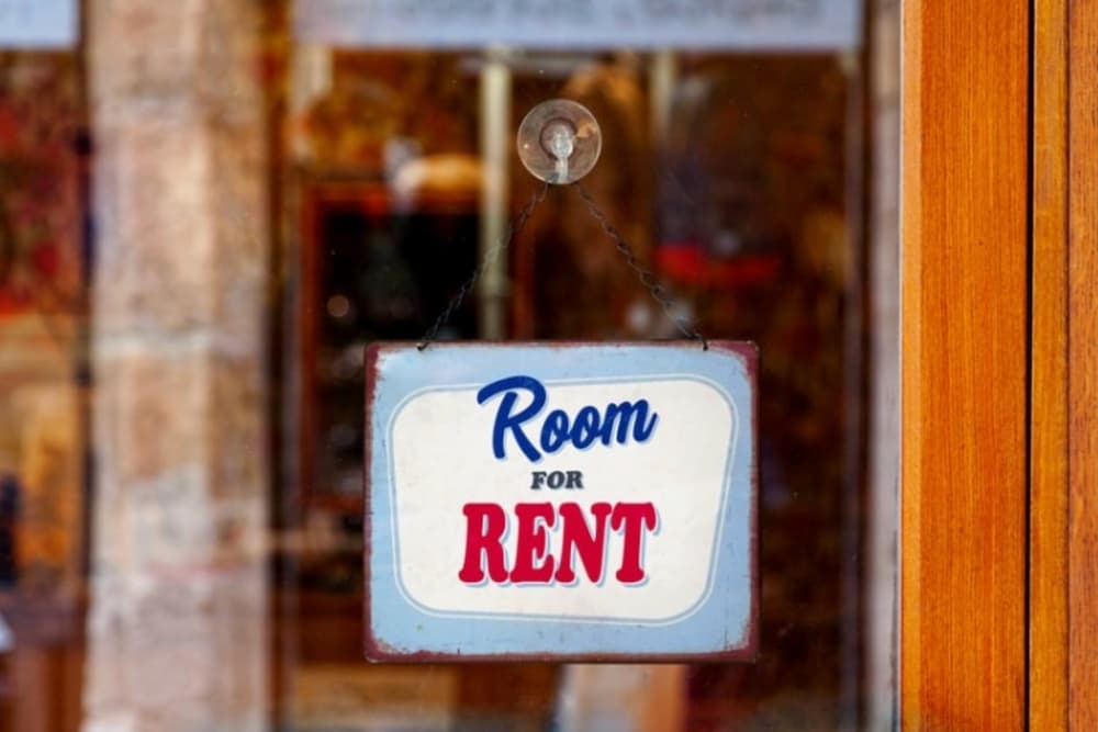 An image of a room for rent sign hanging on a glass door