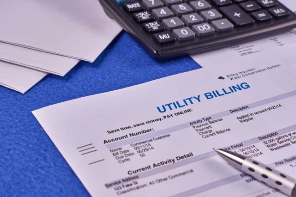An image of a calculator and pen on top of a utility billing document