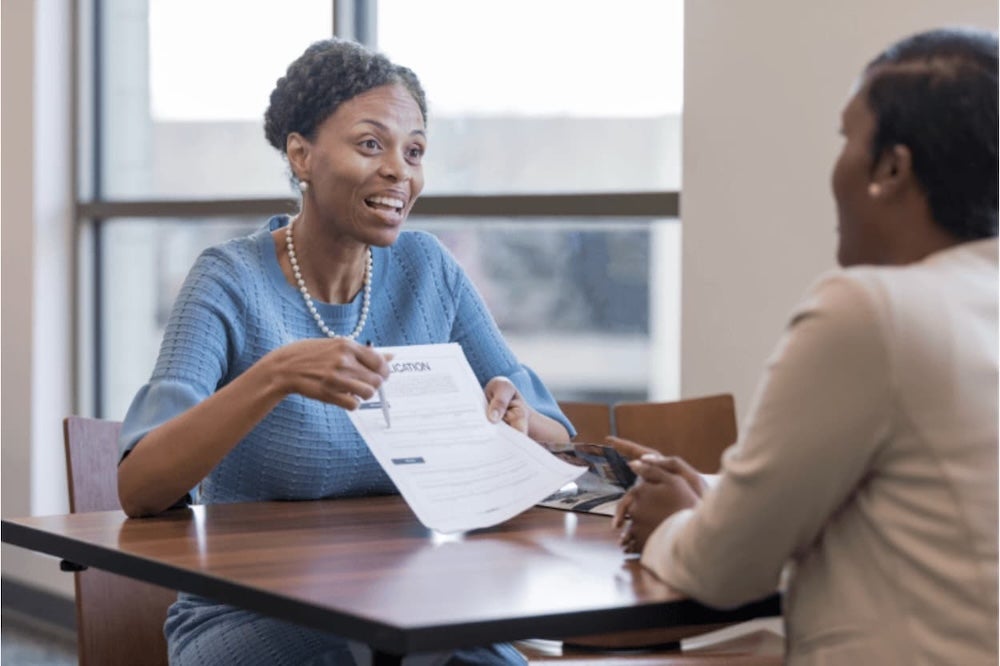 Two people sitting across a desk discussing an application