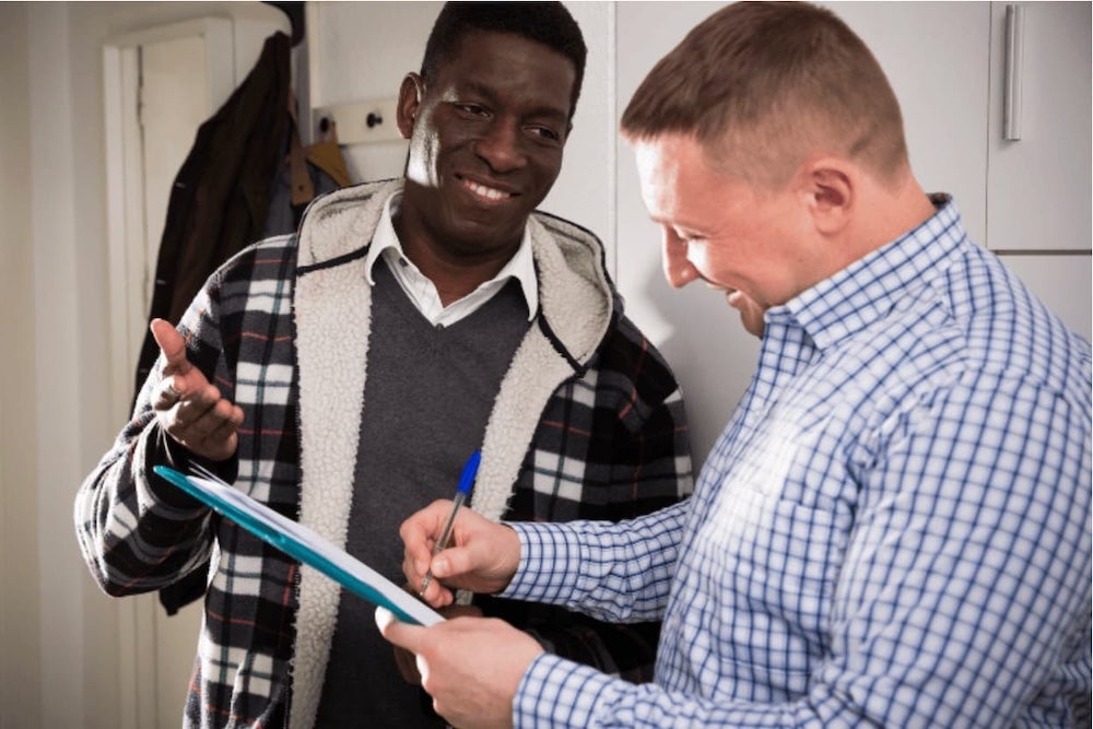 Two people signing a document on a clipboard
