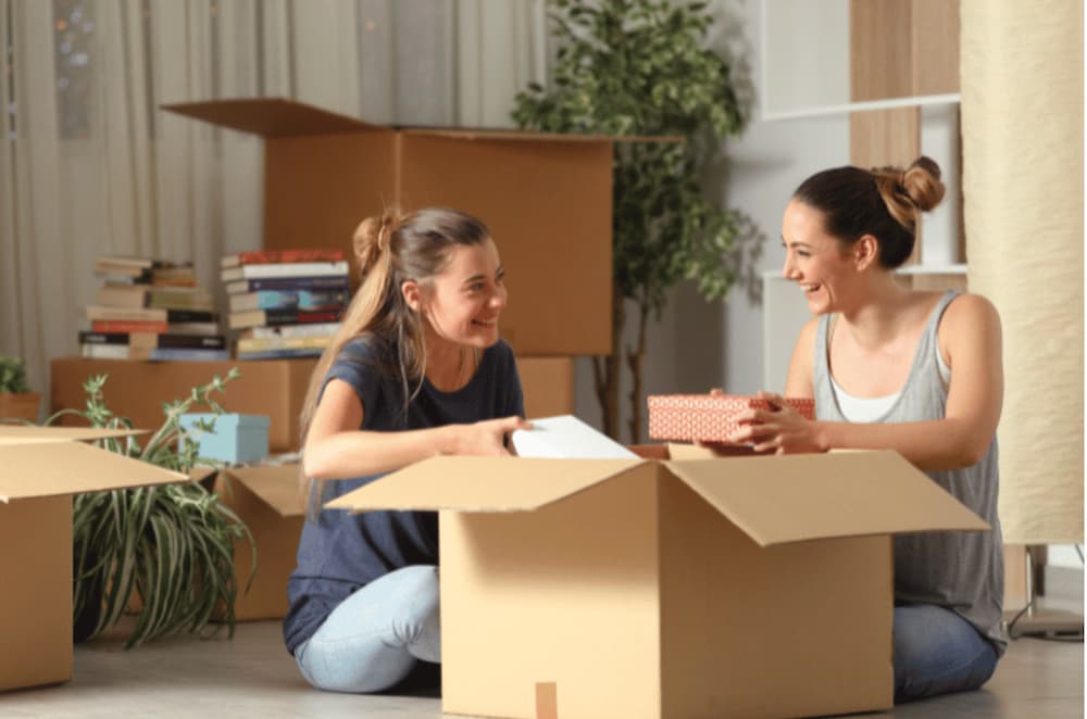 An image of two people unpacking moving boxes