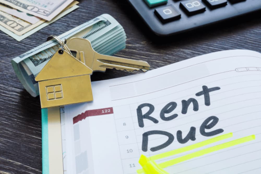 An image of money wrapped up next to house keys and a calender with rent due writted in it